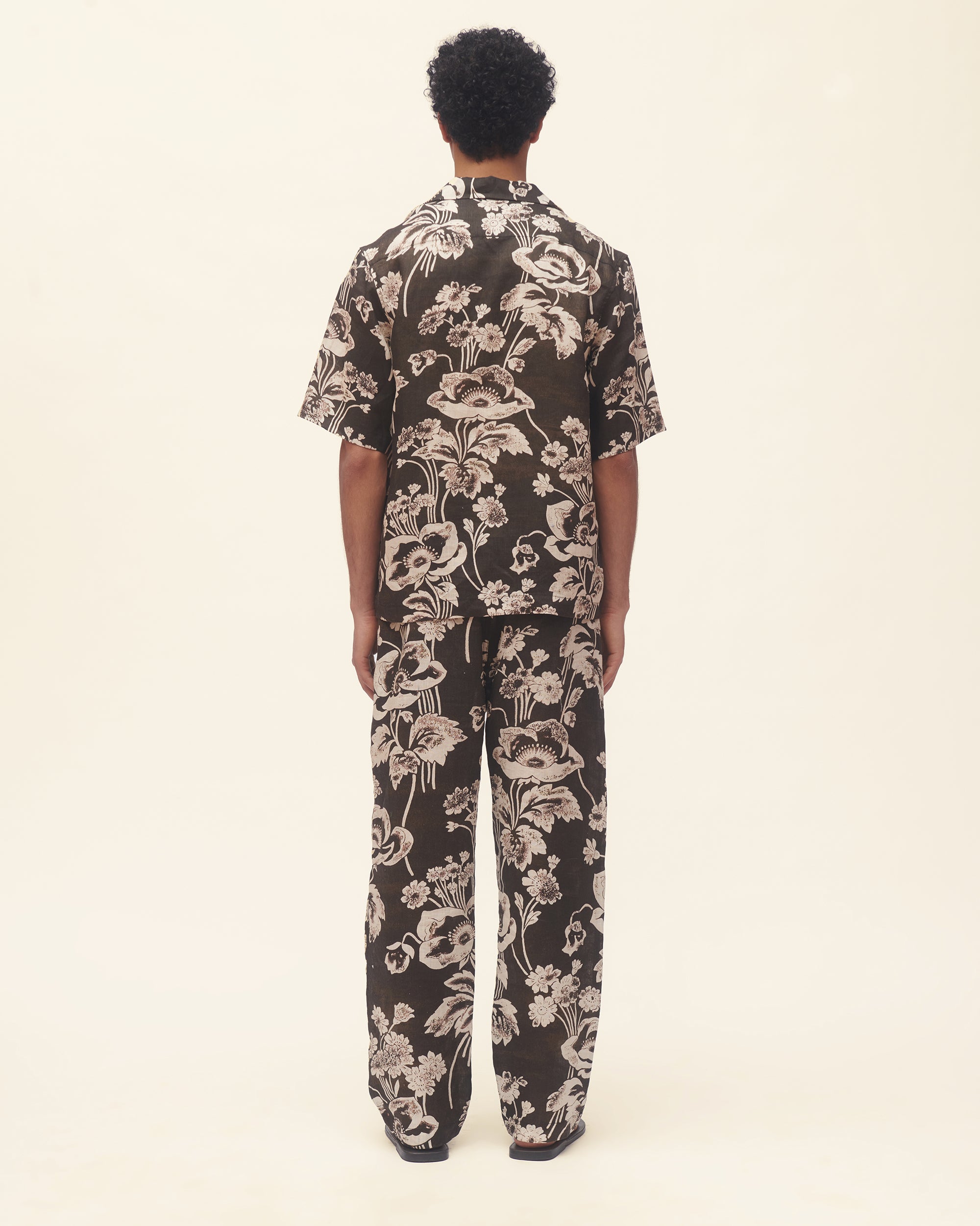 Man wearing a black floral set on a beige background