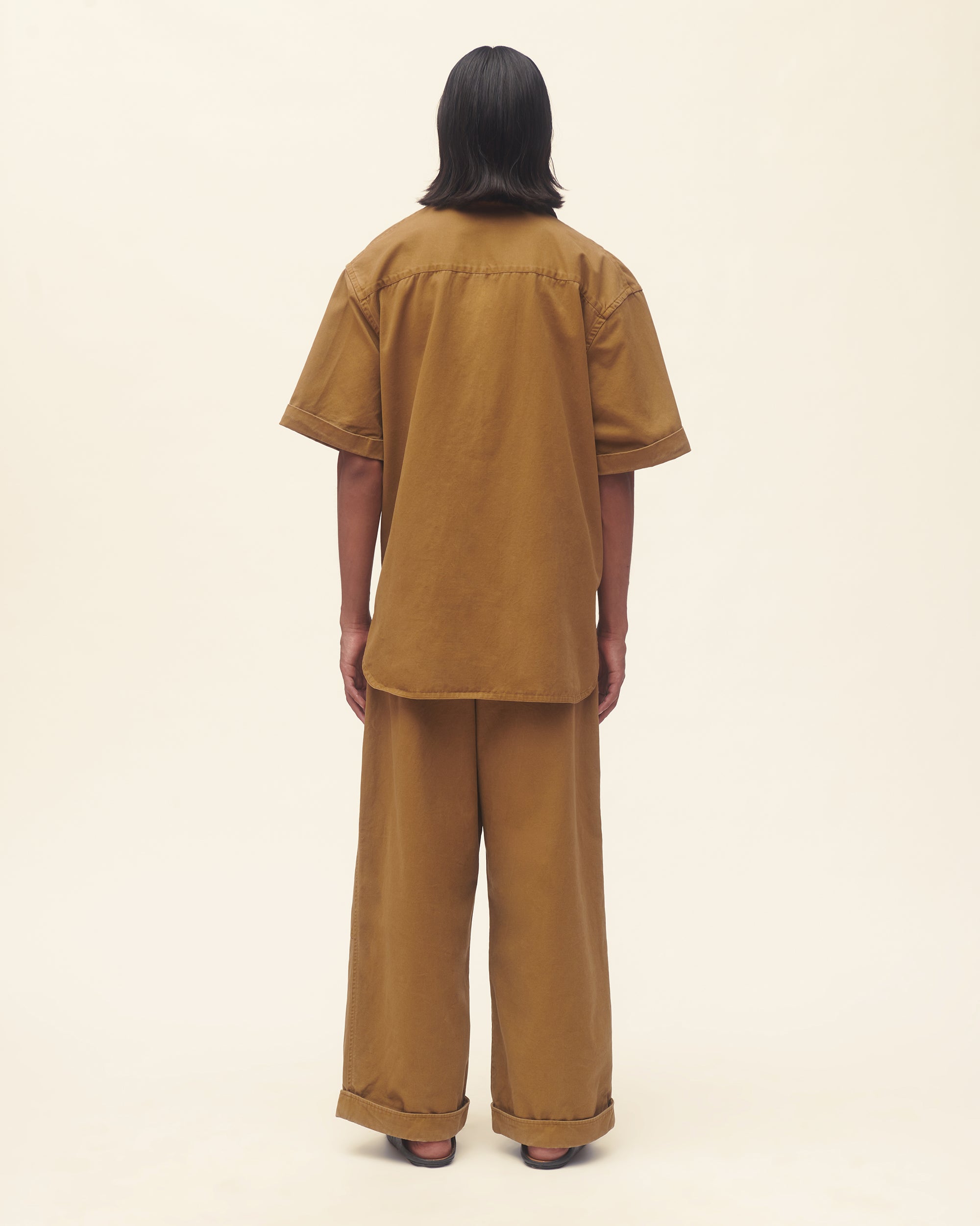 Person wearing a beige outfit on a beige background