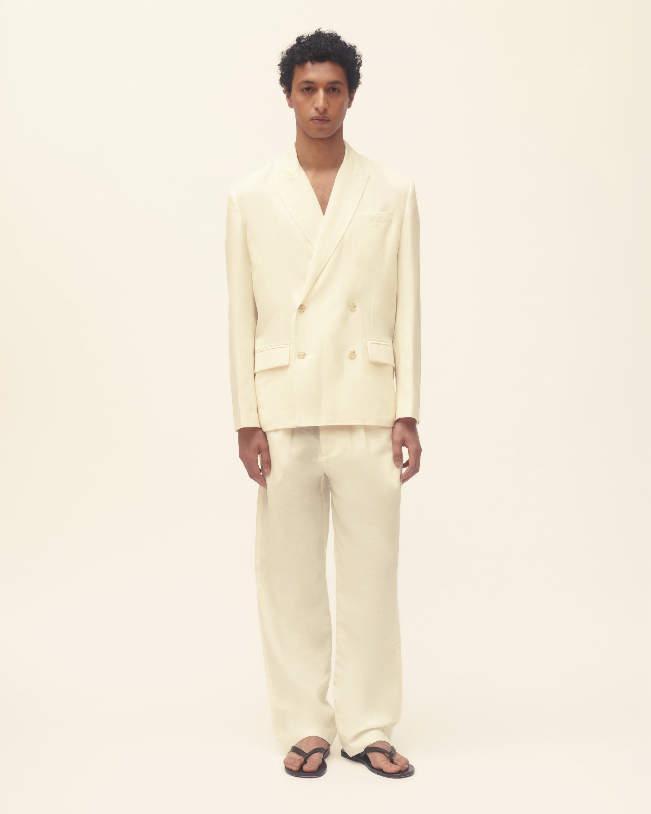 Person wearing a light-colored suit on a plain background