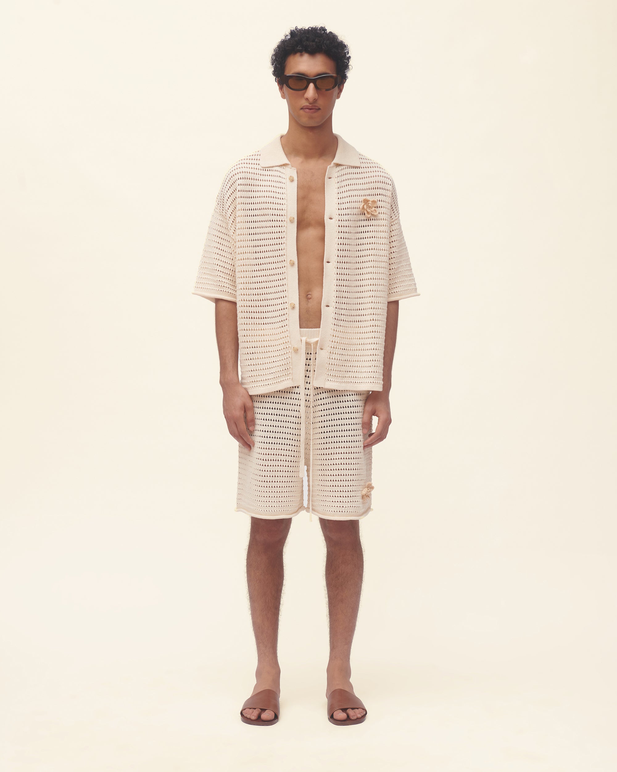 Man wearing a textured beige shirt and shorts set on a plain background