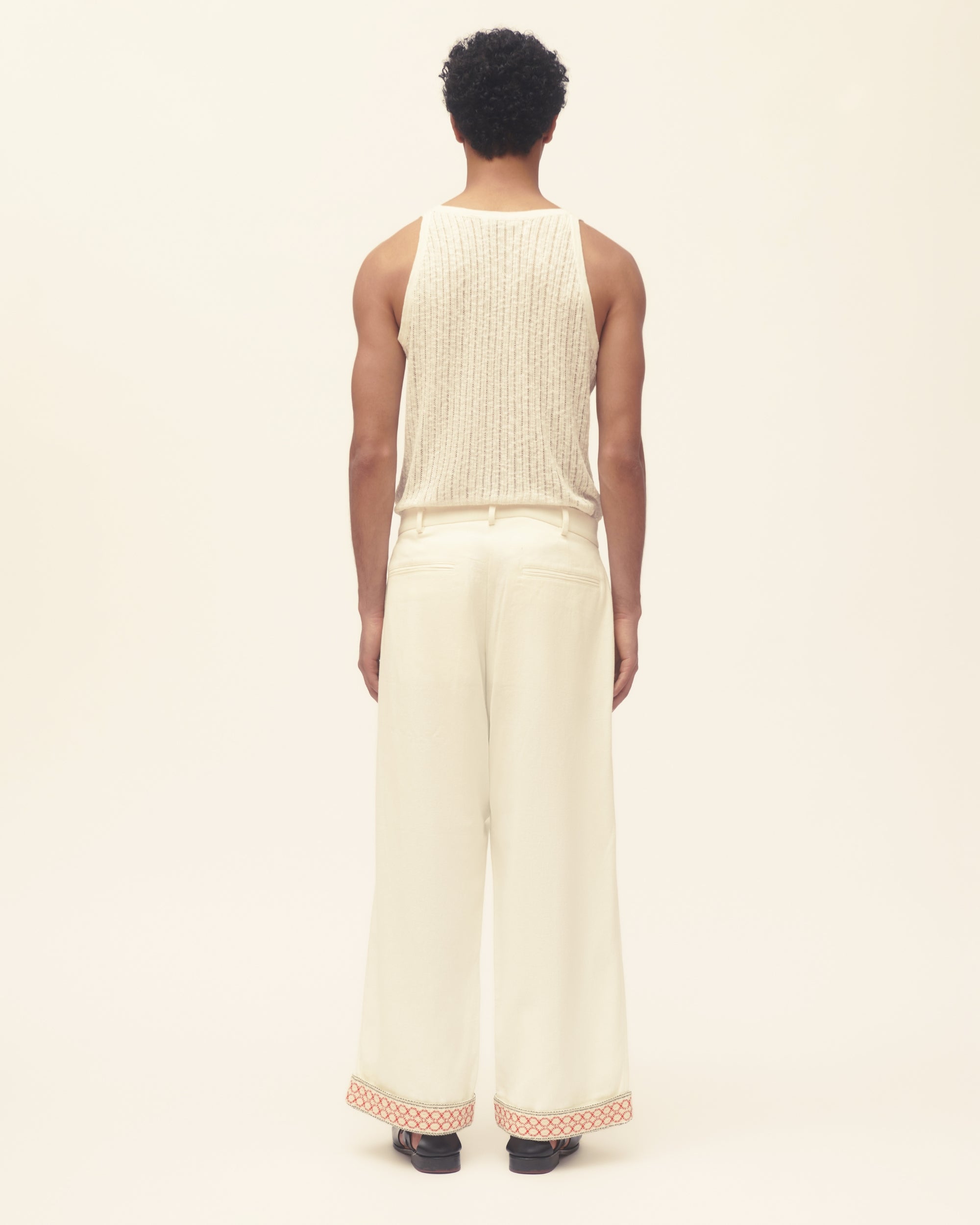 Person wearing a cream sleeveless top and wide-leg pants on a white background