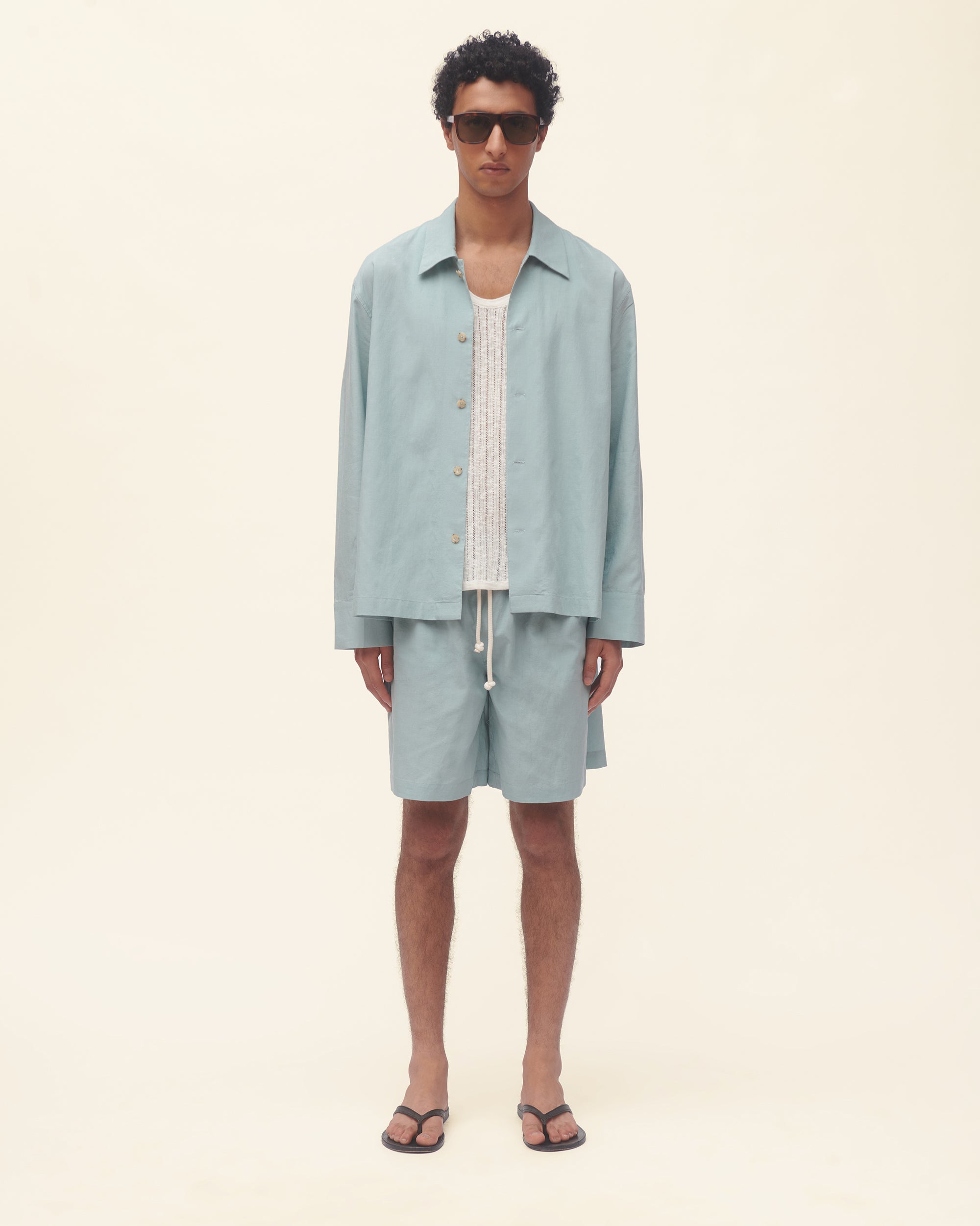 Person wearing a light blue outfit on a beige background