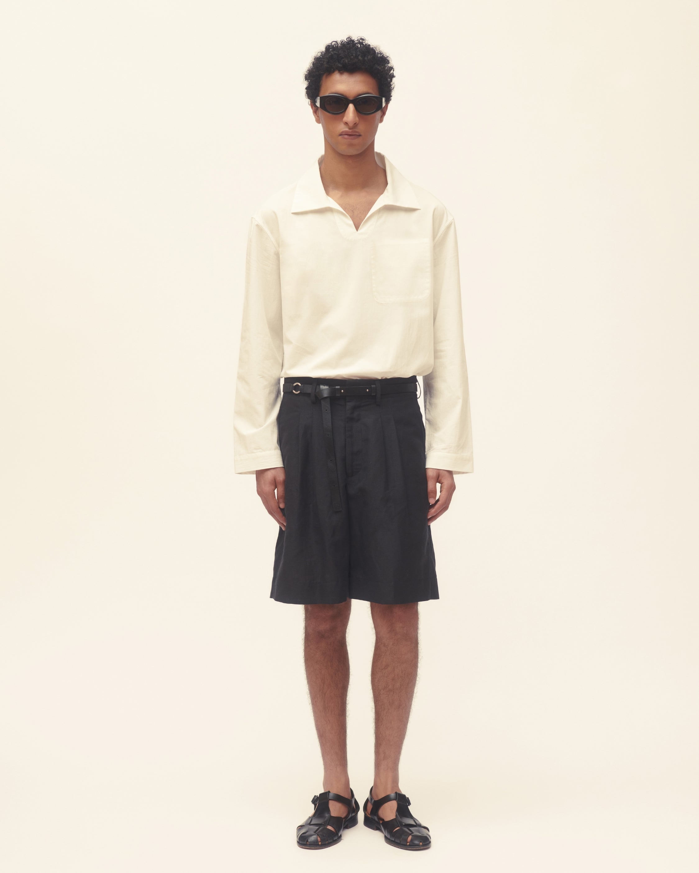 Person wearing a white shirt and black shorrts on a plain background