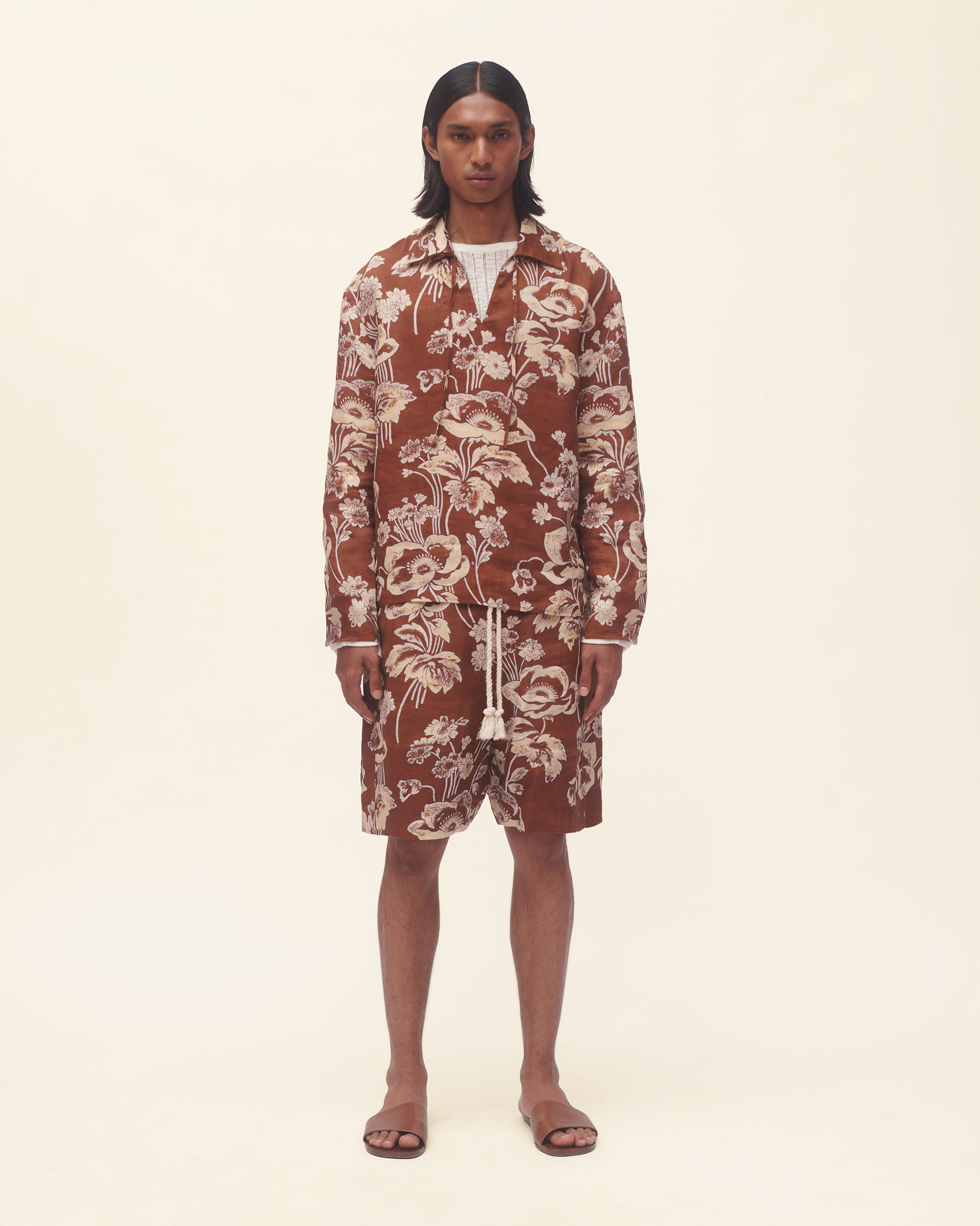 Person wearing a floral patterned outfit on a beige background