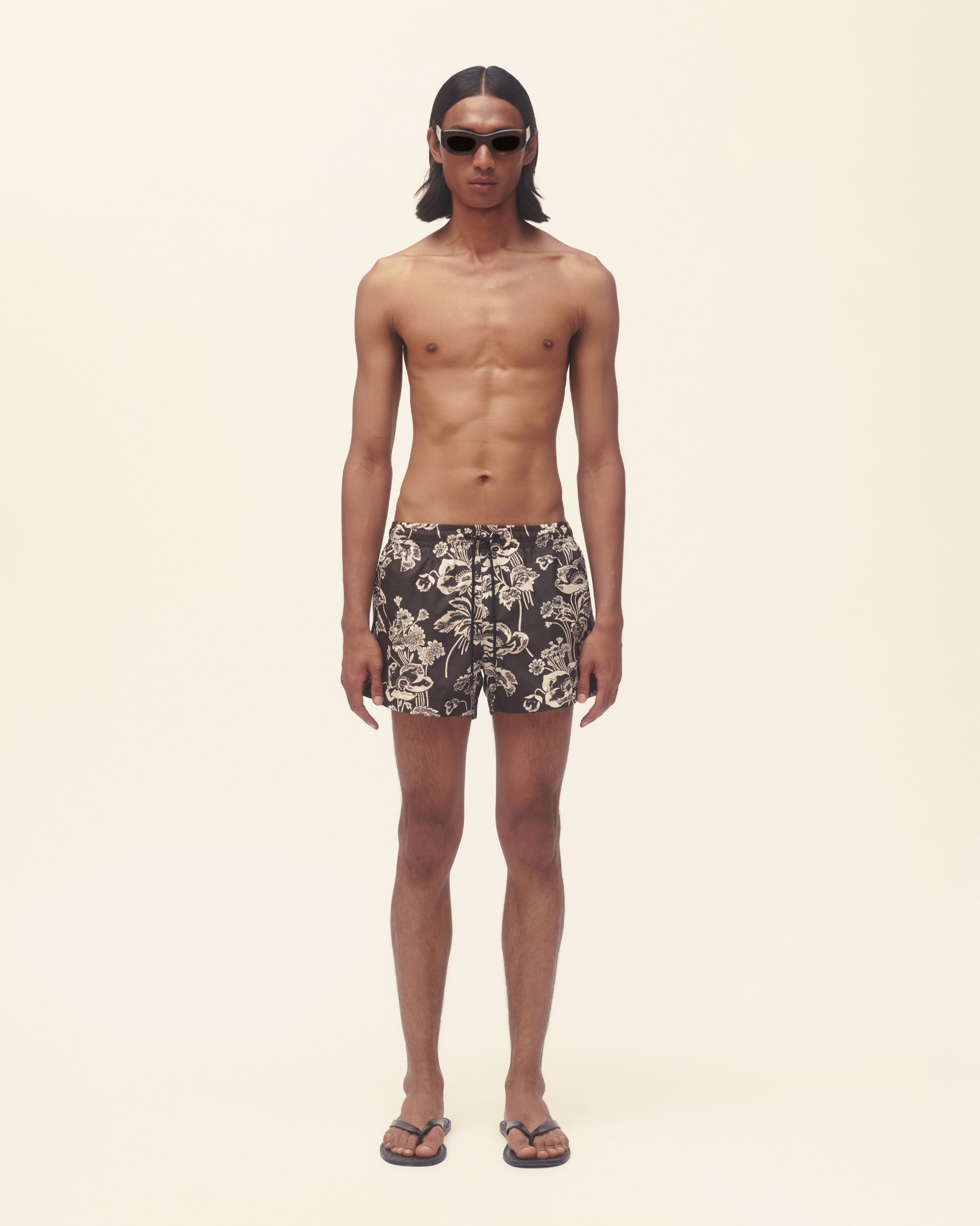 Man wearing patterned swim shorts on a plain background