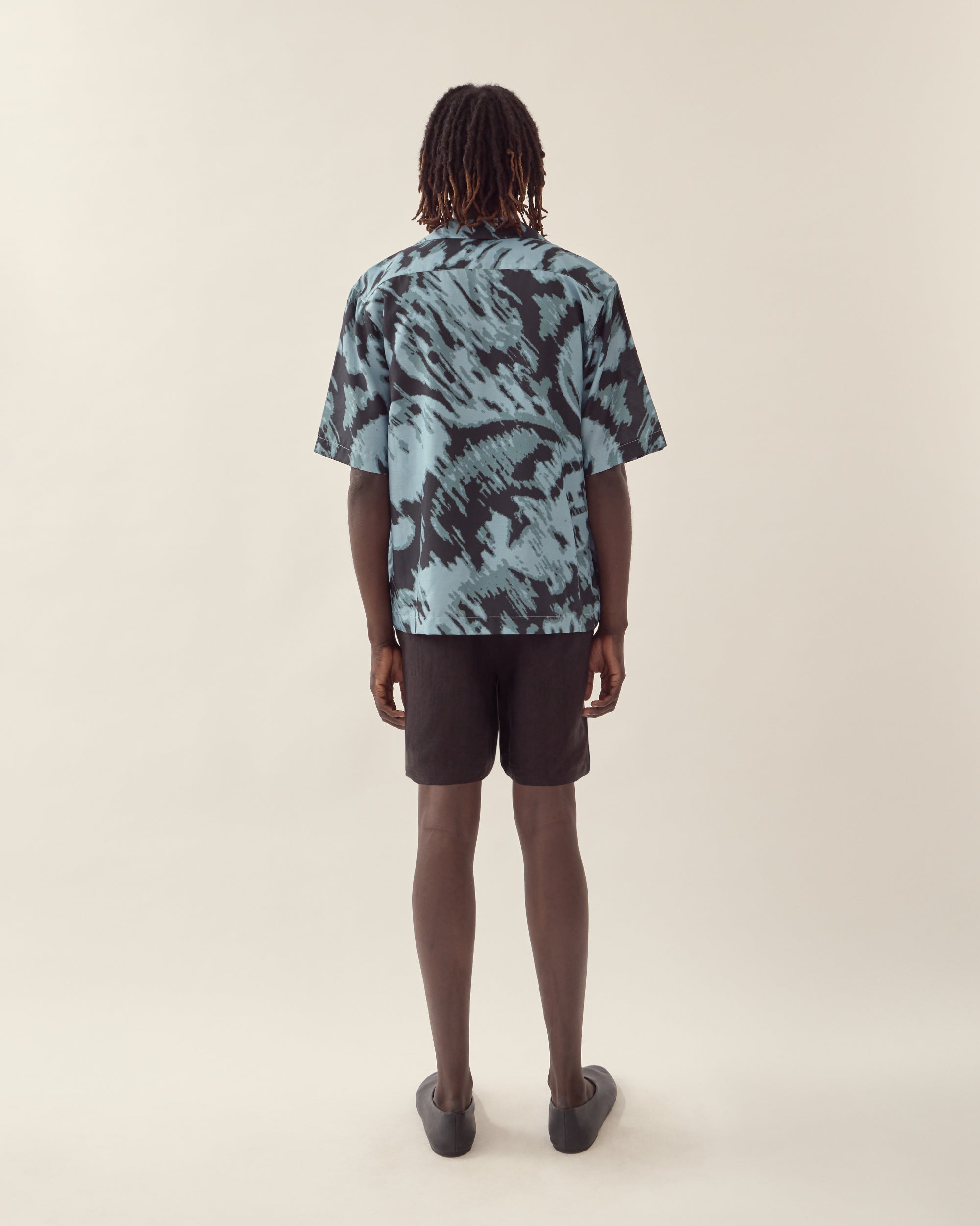 Back view of men's paisley print silk camp collar shirt in navy.