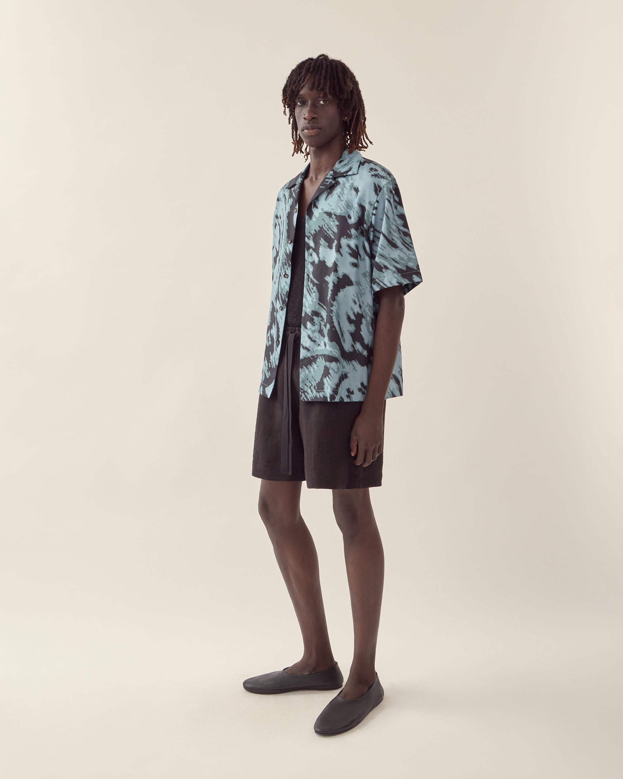 Side view of men's paisley print silk camp collar shirt in navy.