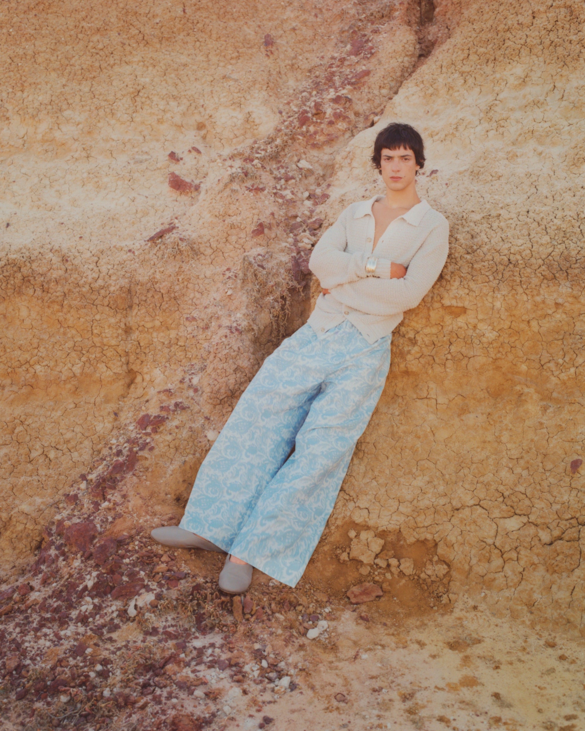 Campaign image of men's trousers and textured knit cardigan.