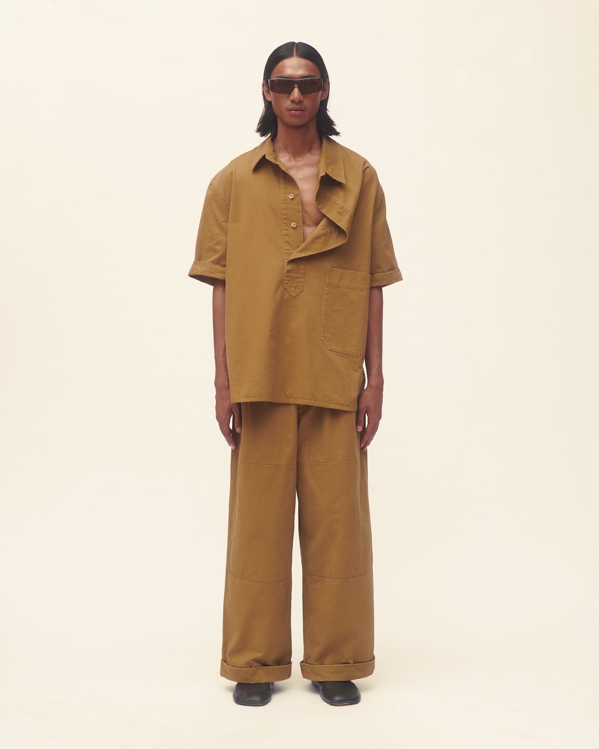 Person wearing a brown outfit on a beige background