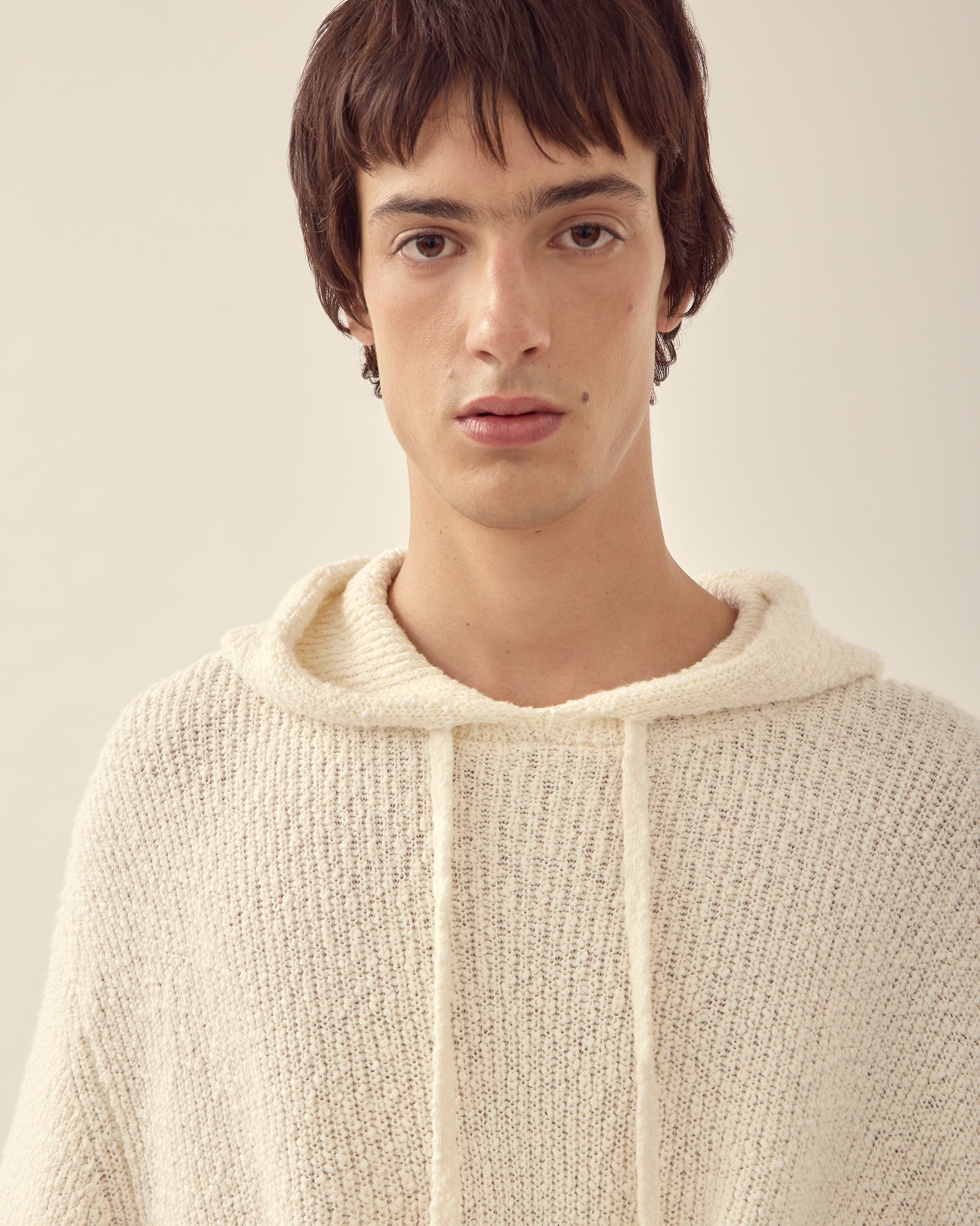 Close view of men's relaxed knit hoodie in white.