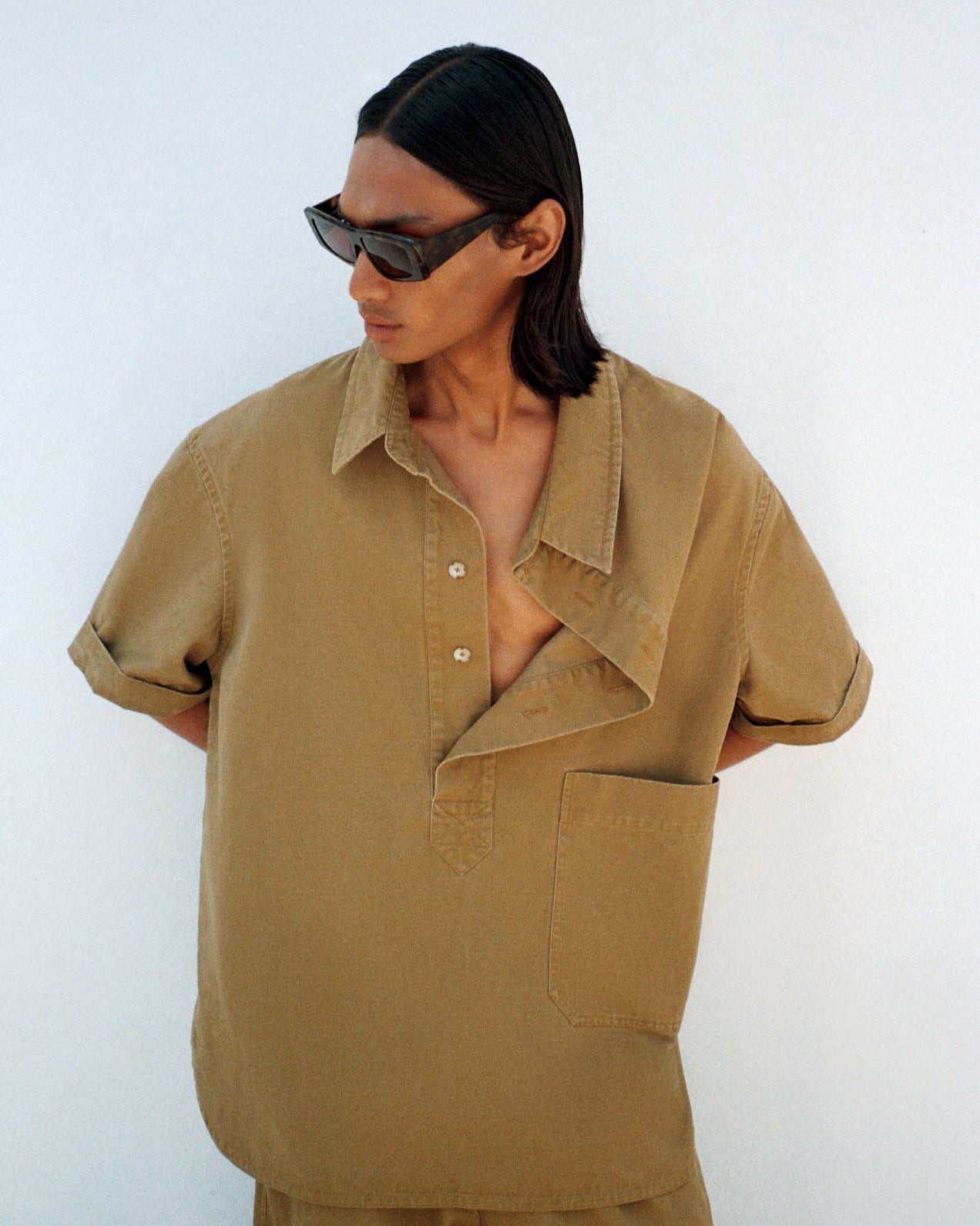 Person wearing a beige shirt with a white background