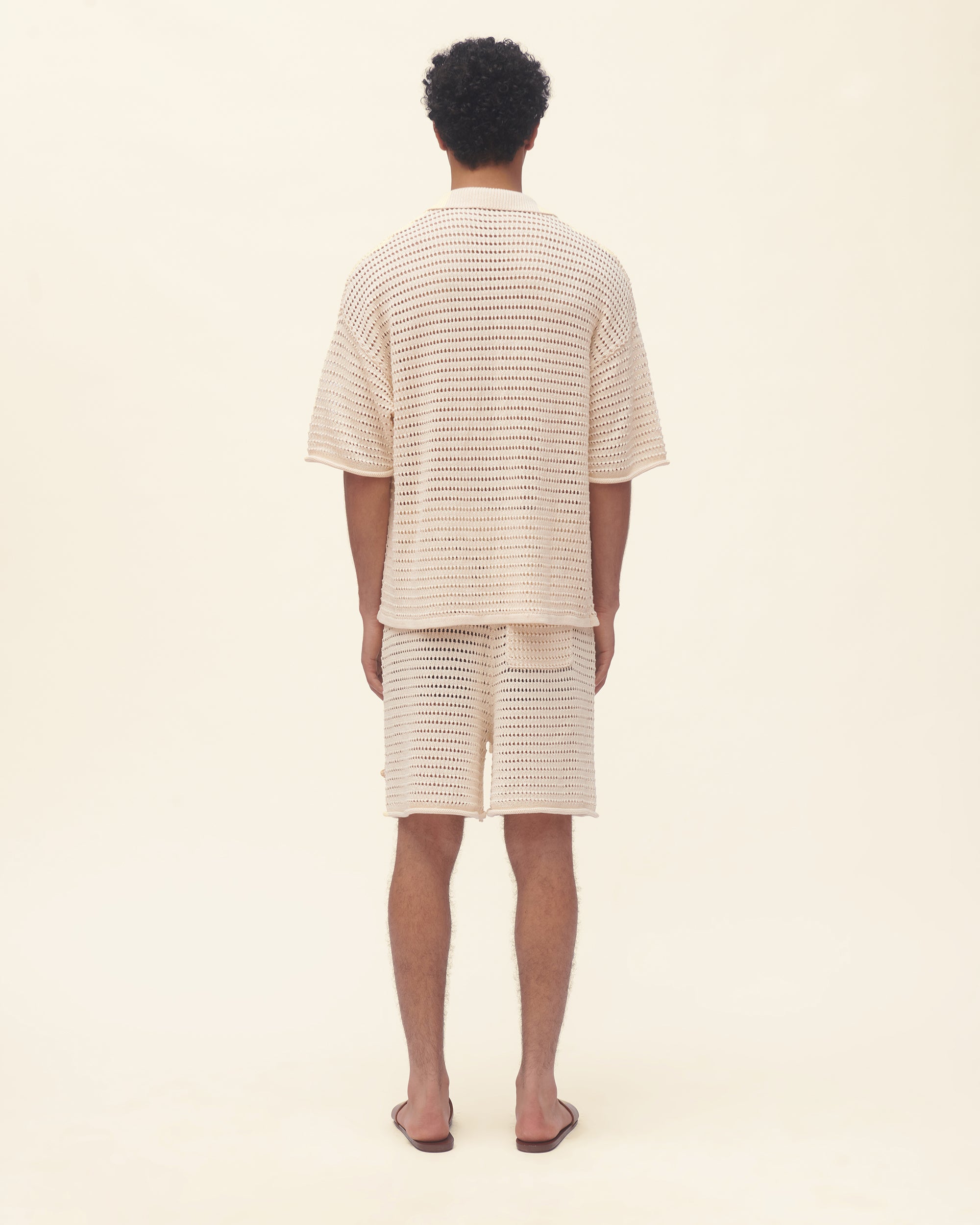 Person wearing a matching beige outfit with a textured pattern on a plain background