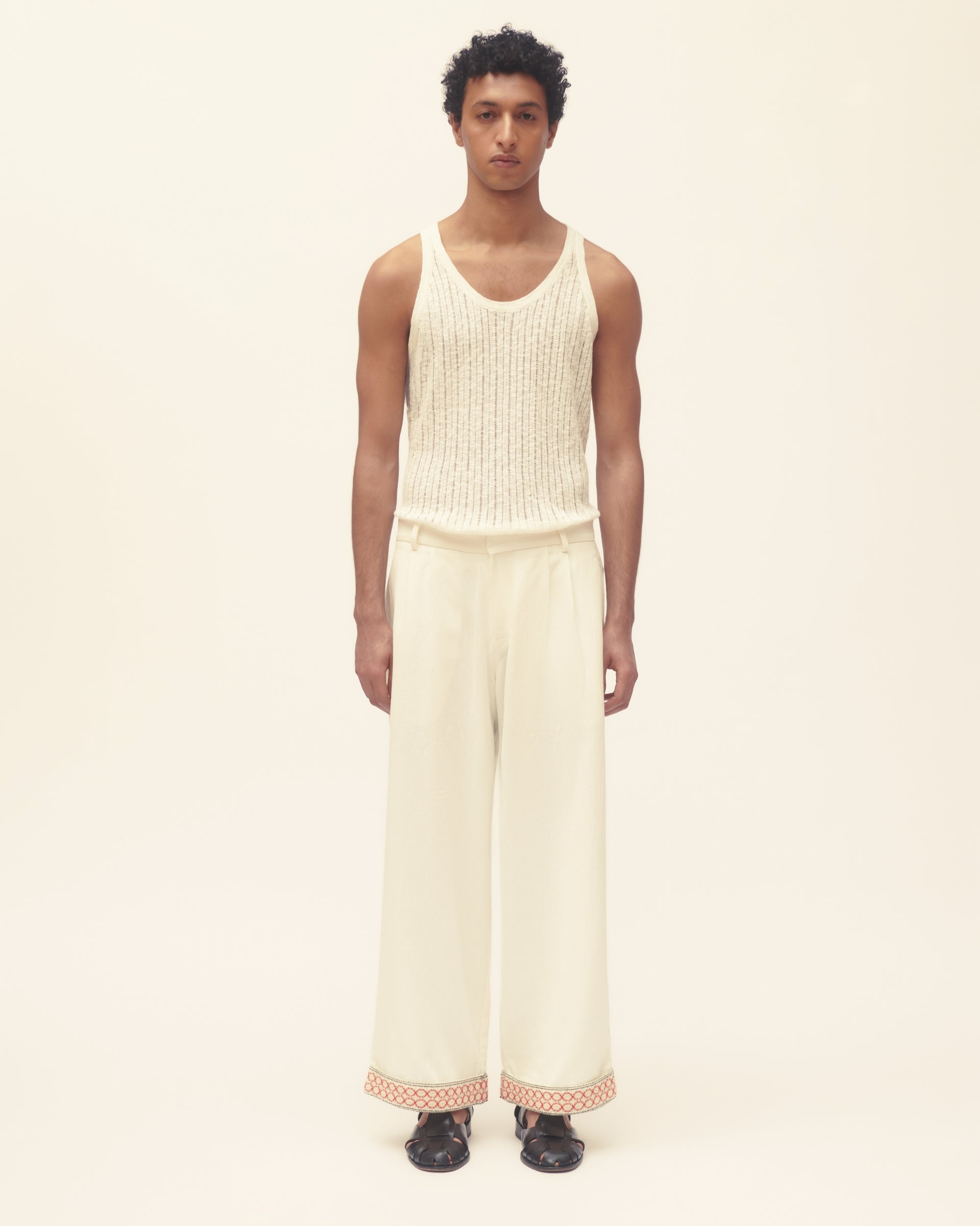 Person wearing a cream sleeveless top and wide-leg pants on a white background