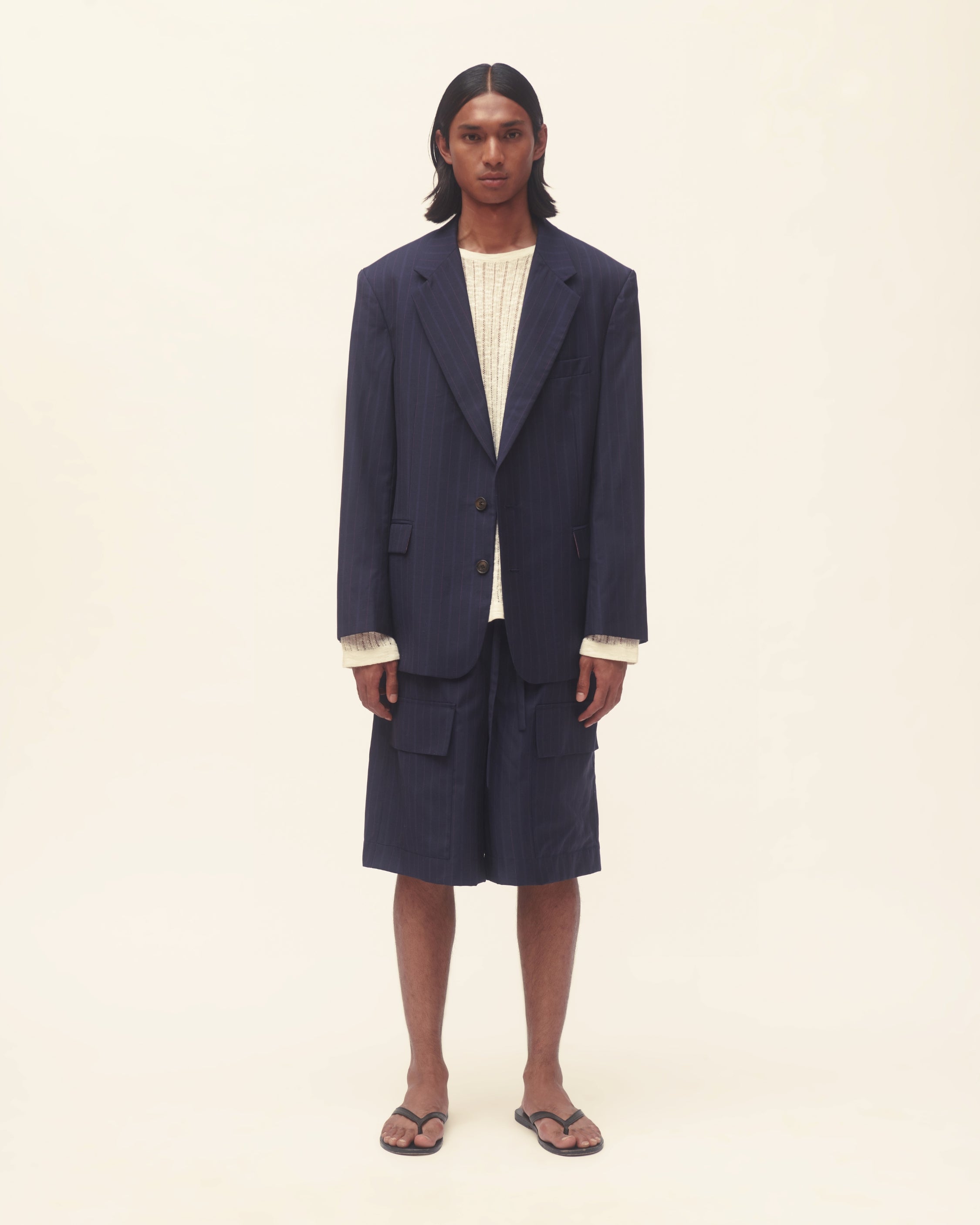 Person wearing a navy blue jacket over a white shirt on a beige background