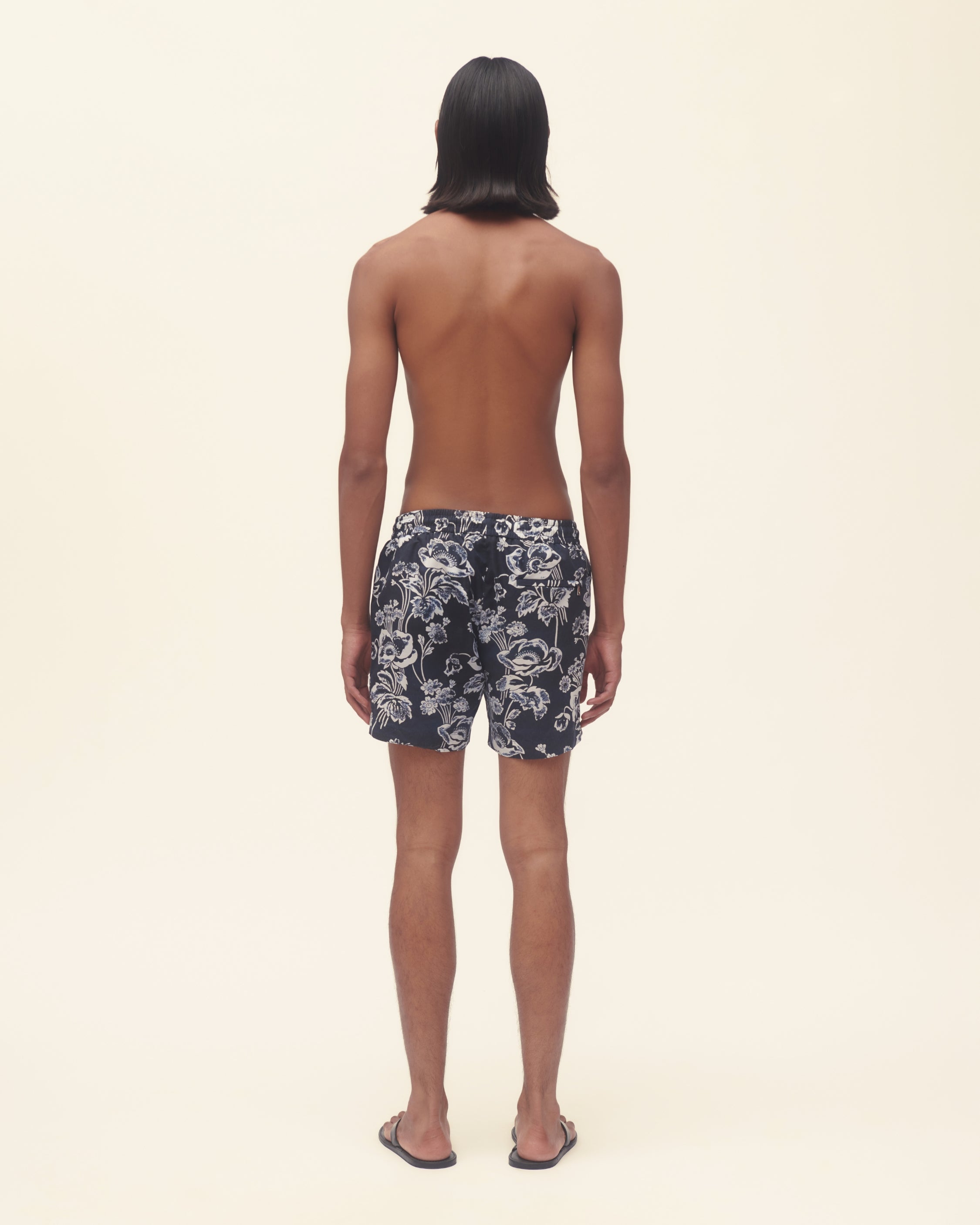 Person wearing floral-patterned shorts on a beige background