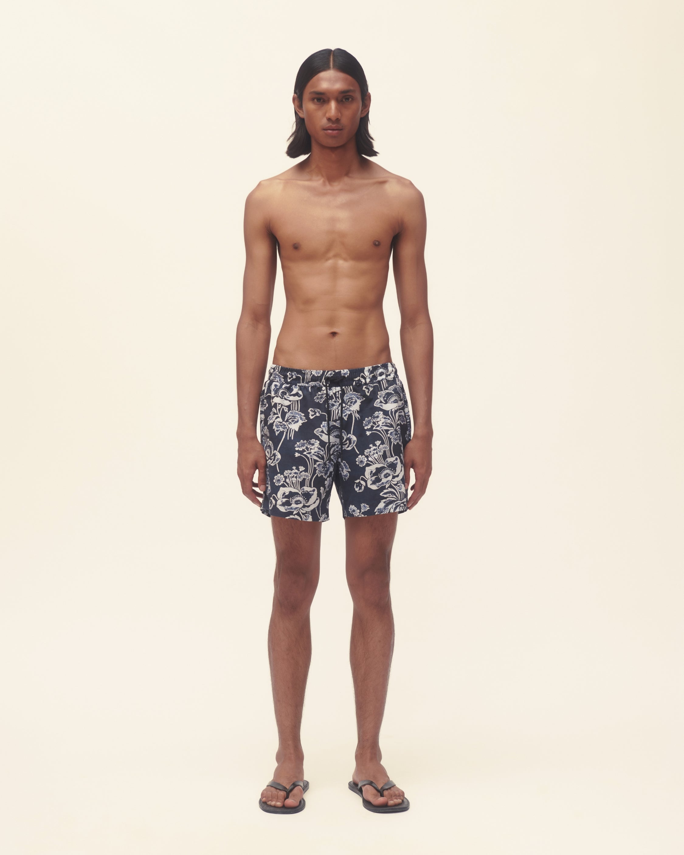 Man wearing floral swim shorts on a plain background