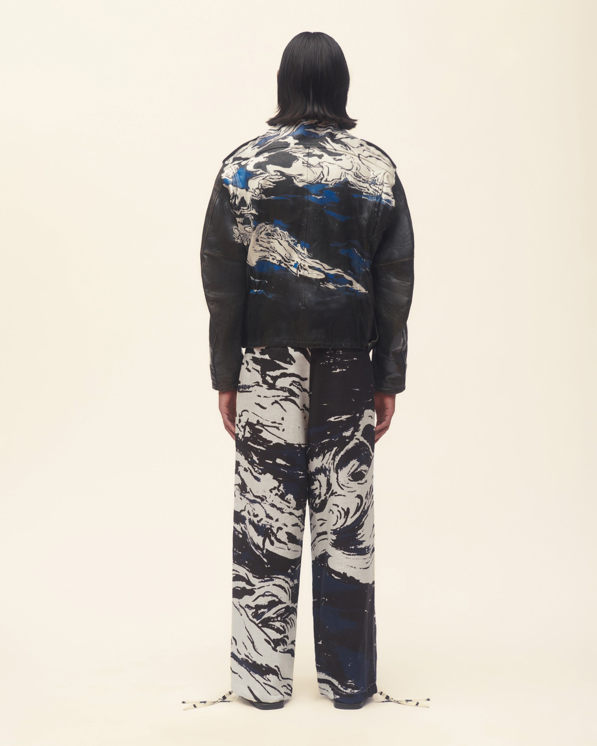 Person wearing a black leather jacket on a beige background