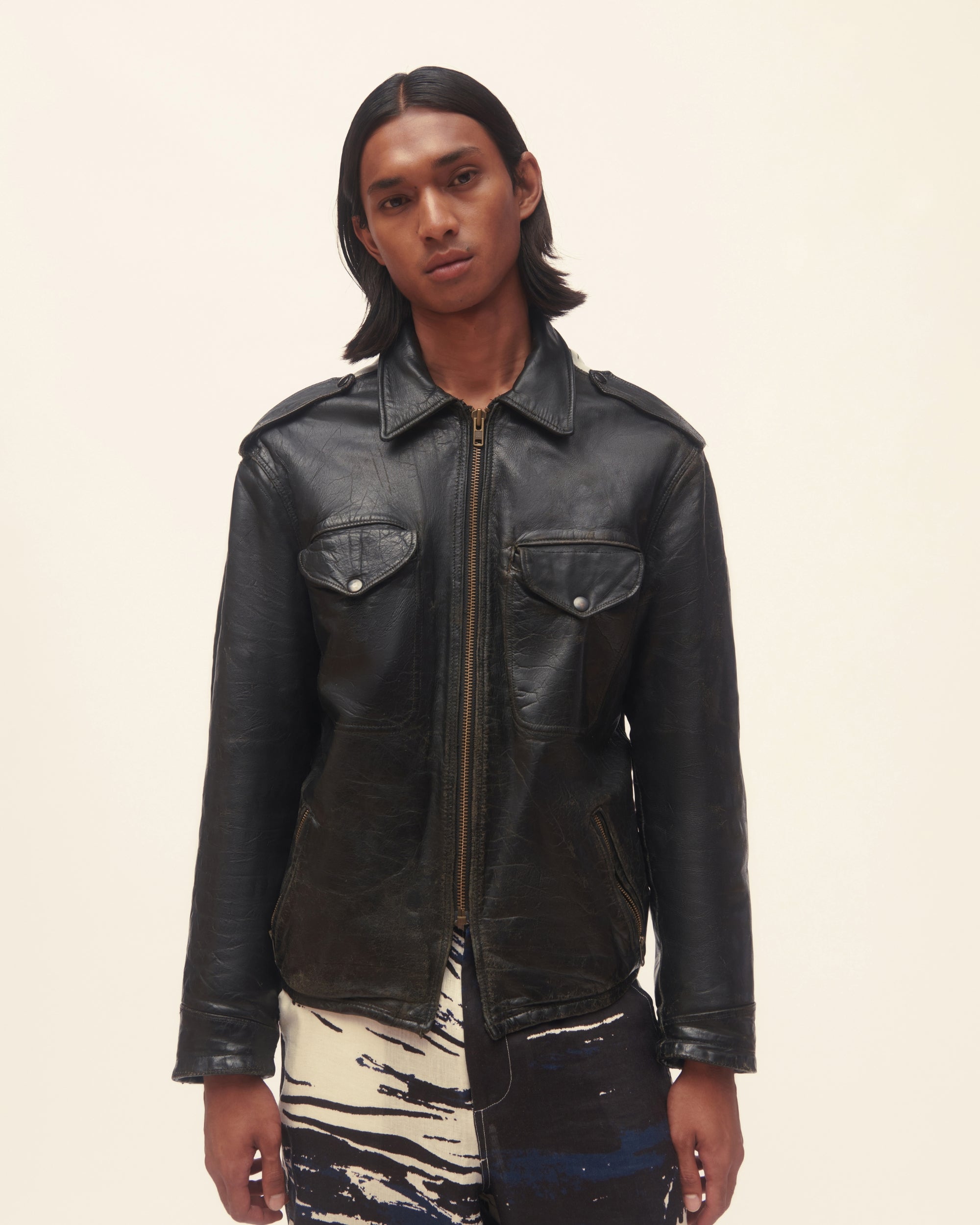 Person wearing a black leather jacket on a beige background